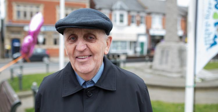 An elderly man wearing a hat smiling at the camera